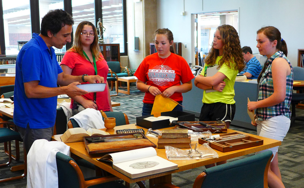 Archivist Gino Pasi explaining the items on the table to a group of Exploring STEMM students, June 22, 2015