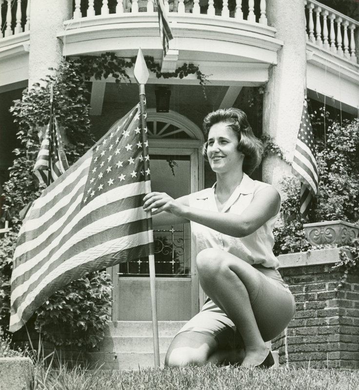 Woman setting out an American flag in front of her home. (Photo from Dayton Daily News Archive)