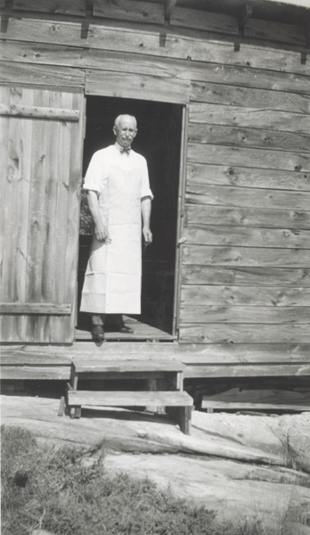 Orville Wright standing in the doorway of his summer home on Lambert Island, ca. 1916-1939. (ms1_26_3_187)