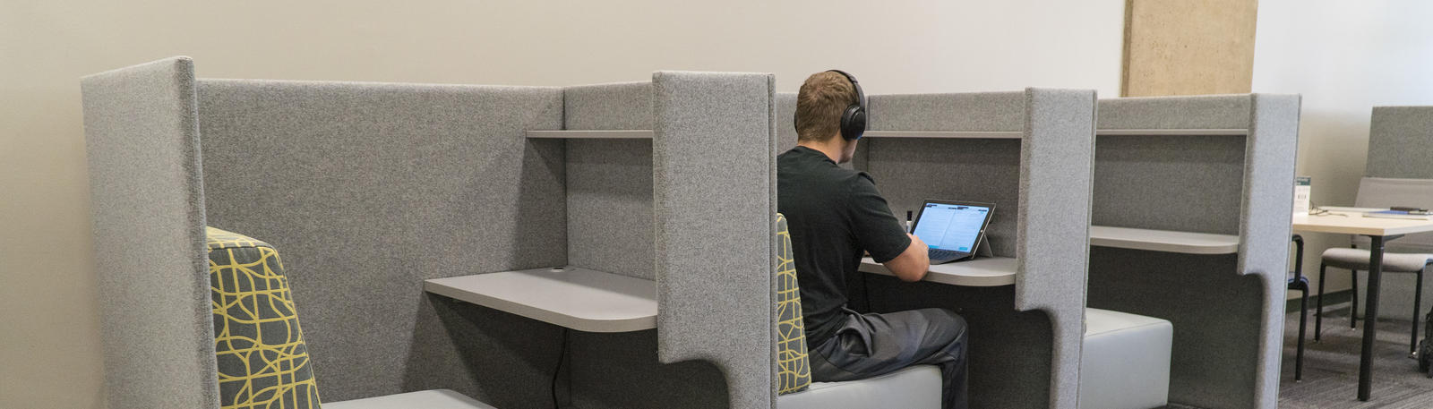 photo of a student with headphones and a laptop in the library