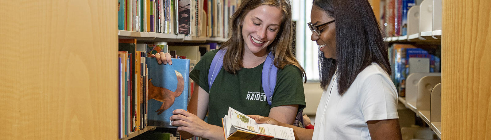 photo of two students looking at a book in the educational resource center